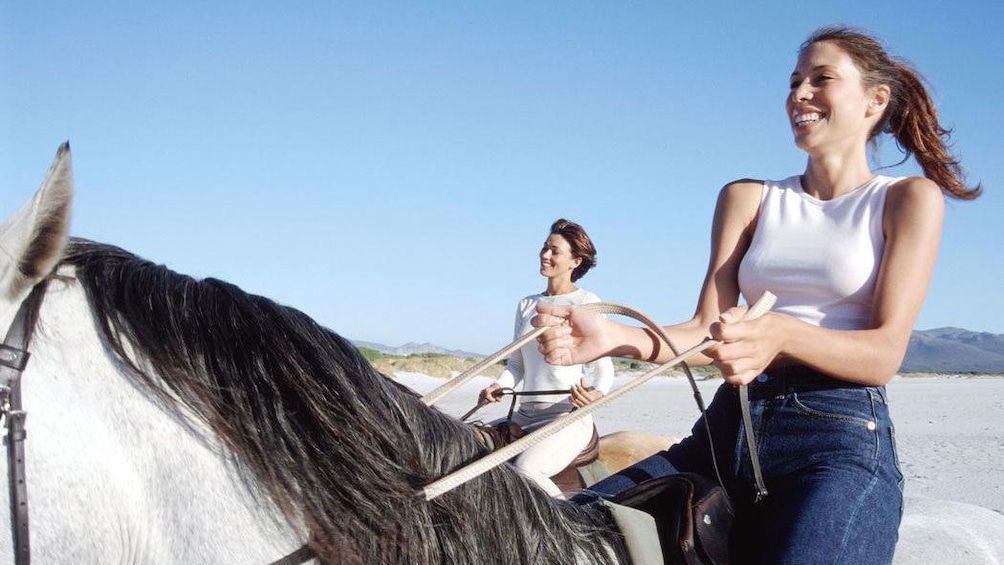 Pair of women riding horseback on the beach in Fiji