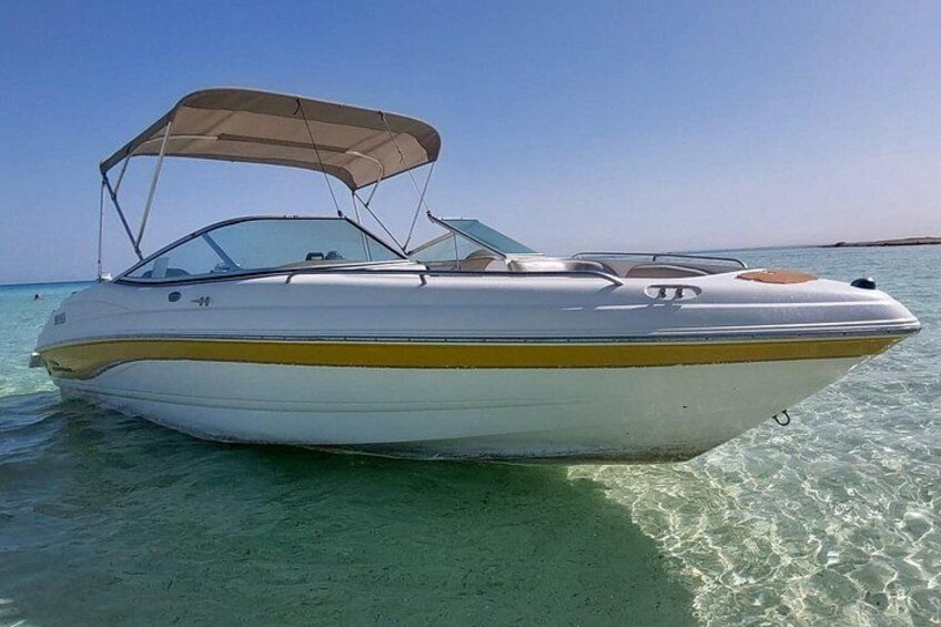 A speedboat with a canopy, floating on clear water. 5