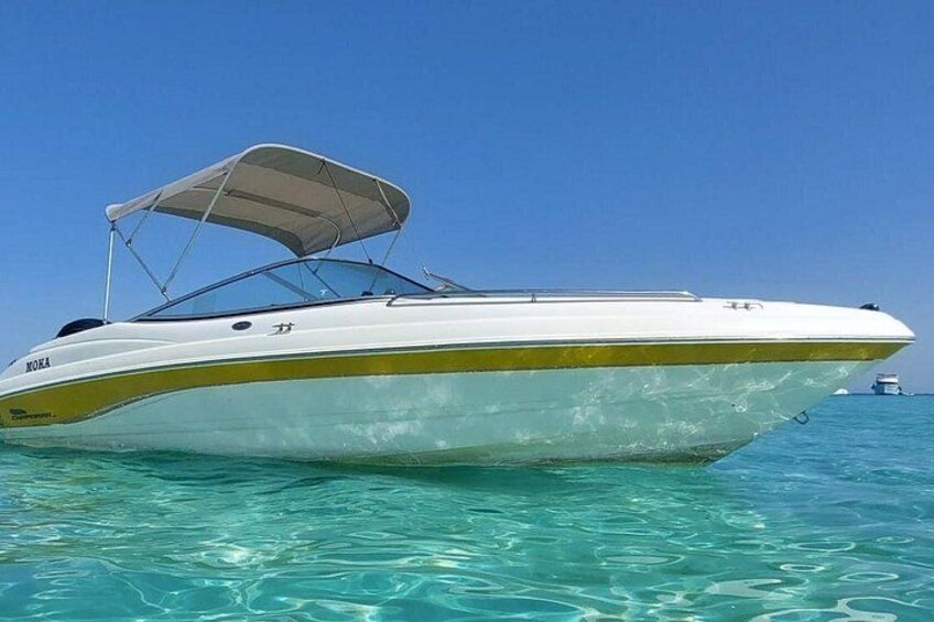 A speedboat with a canopy, floating on clear blue water. 4