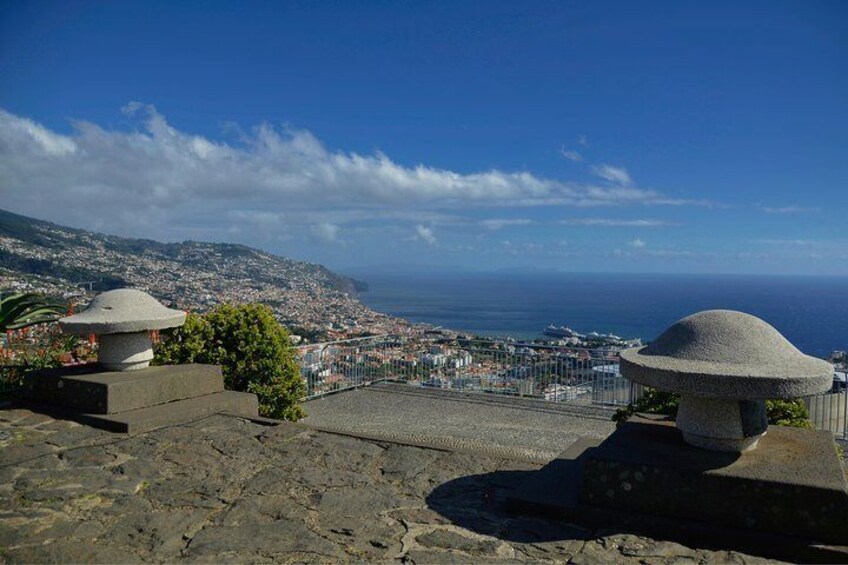A stone staircase leading to a viewpoint overlooking a coastal city with a clear sky. 2