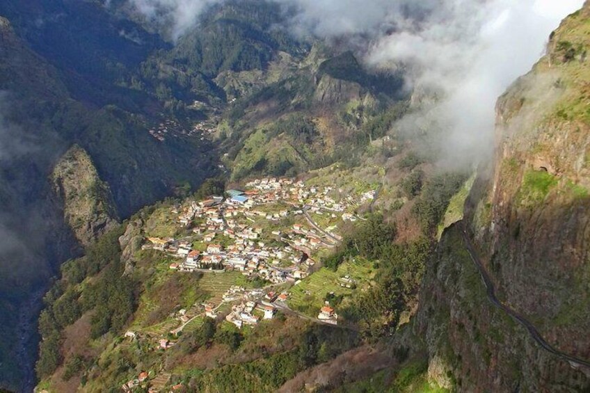 A mountainous village nestled in a valley with steep cliffs and a winding road. 3