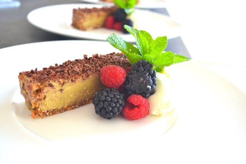 A slice of cheesecake with chocolate shavings and fresh berries on a white plate. 2