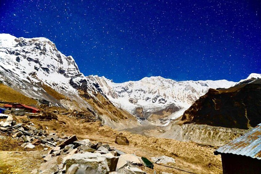 A starry night sky over a mountainous landscape with snow-covered peaks and a rocky foreground. 3