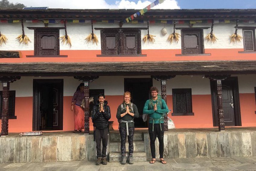 A traditional building with a red and white facade, wooden doors, and a balcony with prayer flags. 5