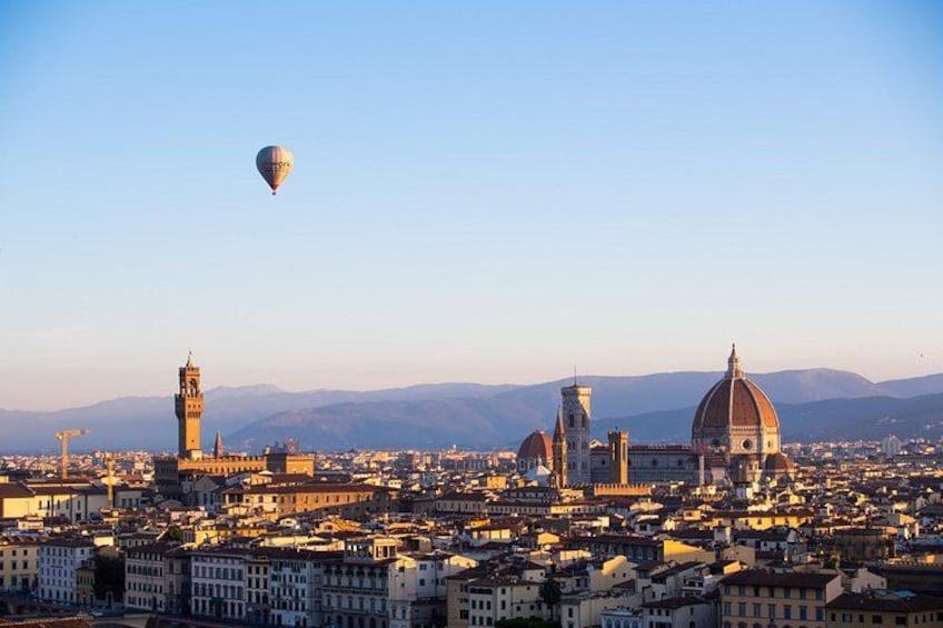 Eine Stadtansicht mit einer markanten Kuppel und einem Heißluftballon am Himmel. 2