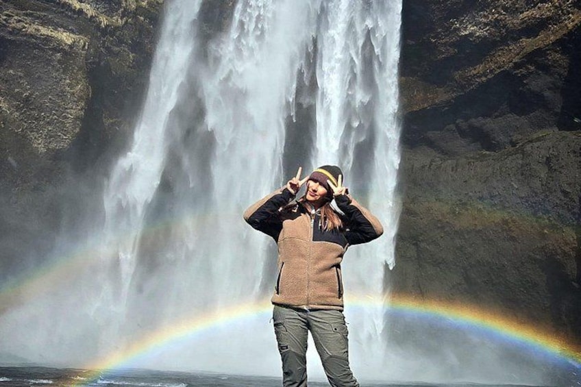 Una persona de pie frente a una cascada con un arcoíris. 2