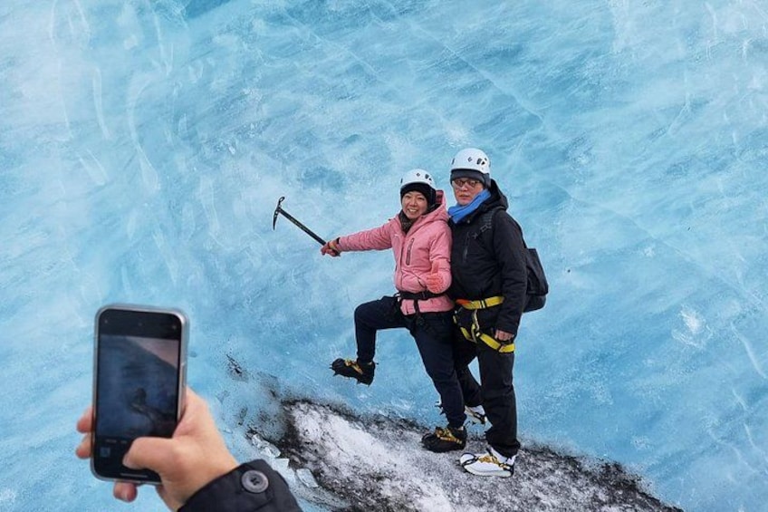Två personer på en frusen yta, den ena håller i en hammare och den andra tar en selfie. 2