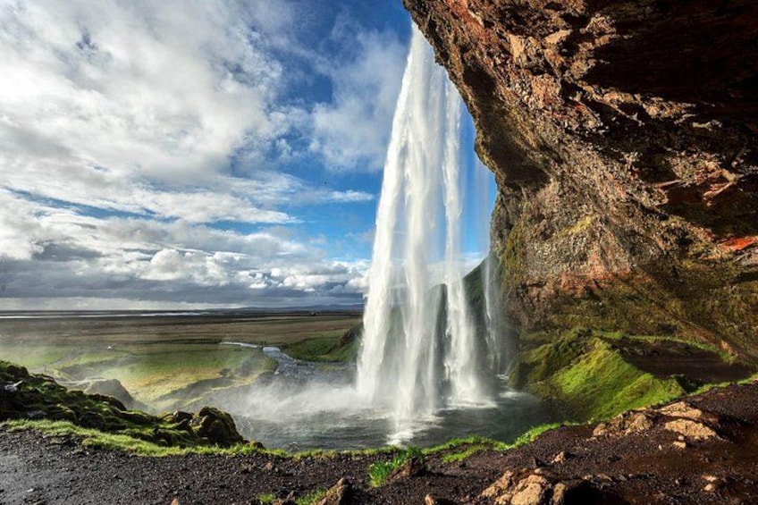 A waterfall cascading down a rocky cliff into a green valley. 4
