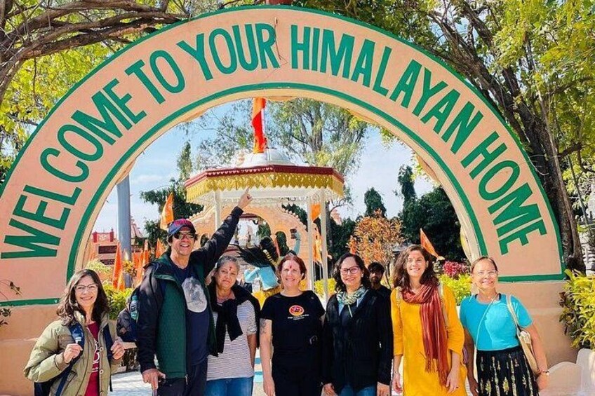 Un grupo de personas de pie bajo un cartel que dice 'BIENVENIDOS A SU HIMALAYAN HOME'. 2