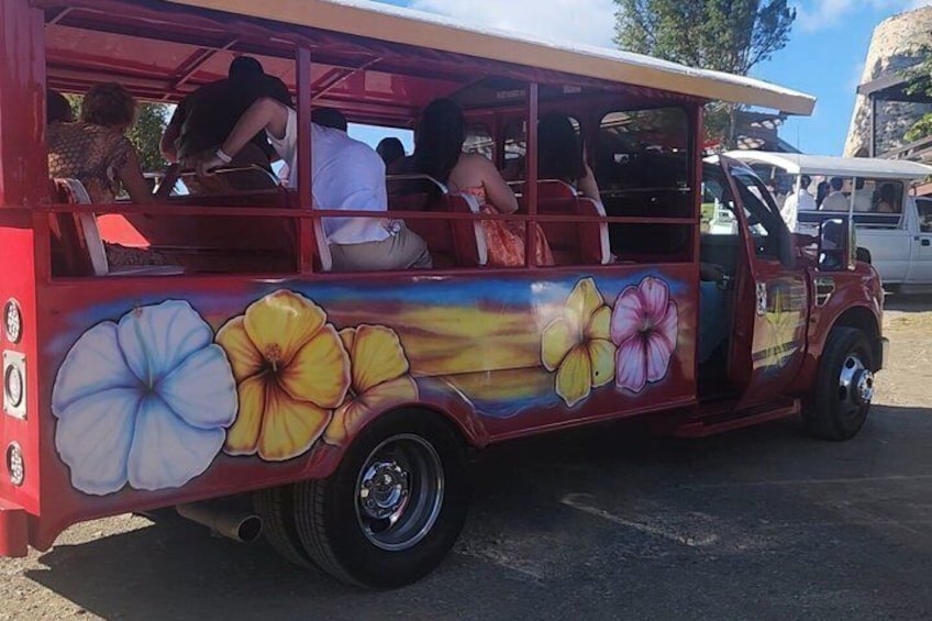 Un autobús rojo con llamativos diseños florales a los lados, estacionado en una calle. 3