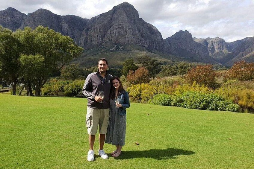 Un couple se tient debout dans un champ d’herbe, avec des montagnes en arrière-plan. 2