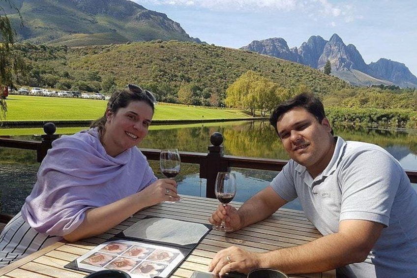 Deux personnes sont assises à une table, devant un paysage magnifique avec des montagnes et un lac en toile de fond. 1