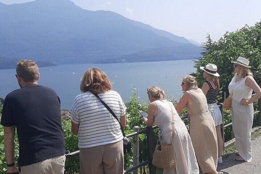 A group of people standing by a lakeside, overlooking a calm lake with mountains in the background. 2