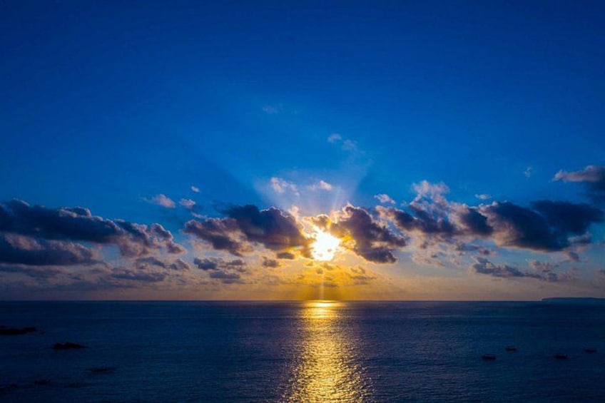 A sunset over a calm sea with clouds reflecting sunlight. 2