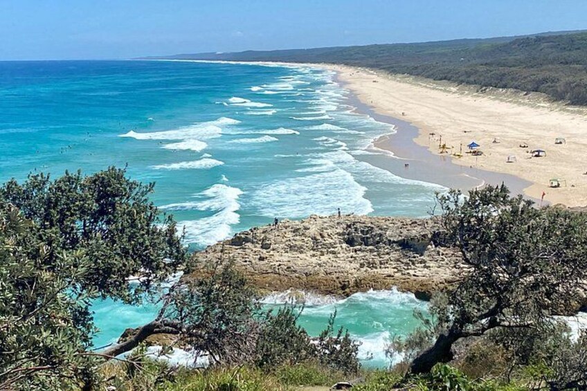 Paesaggio costiero con spiaggia, onde dell'oceano e affioramenti rocciosi. 3