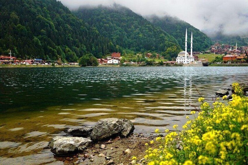 A lake with a mosque, mountains, and a town in the background. 1