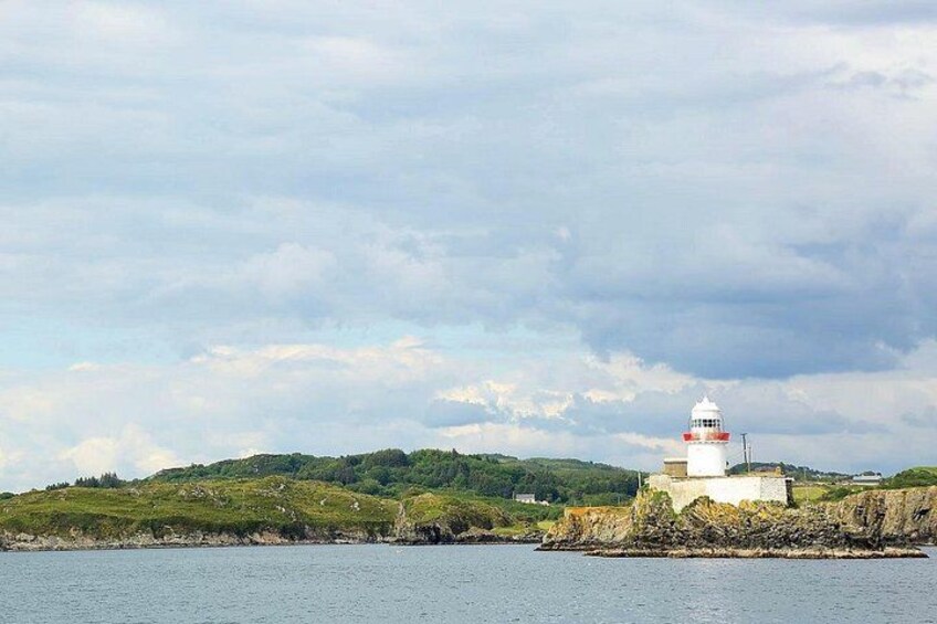 Un faro en un promontorio rocoso con una colina cubierta de hierba al fondo. 3