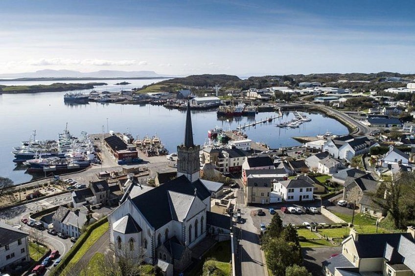 Un pueblo costero con una iglesia destacada, un puerto deportivo con barcos y edificios circundantes. 2