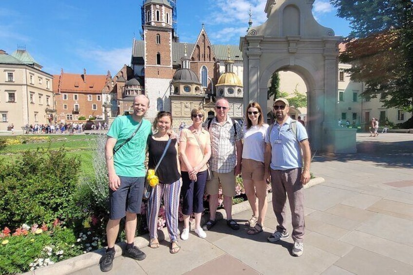 Un grupo de personas frente a un edificio histórico con un arco imponente y una torre del reloj. 1