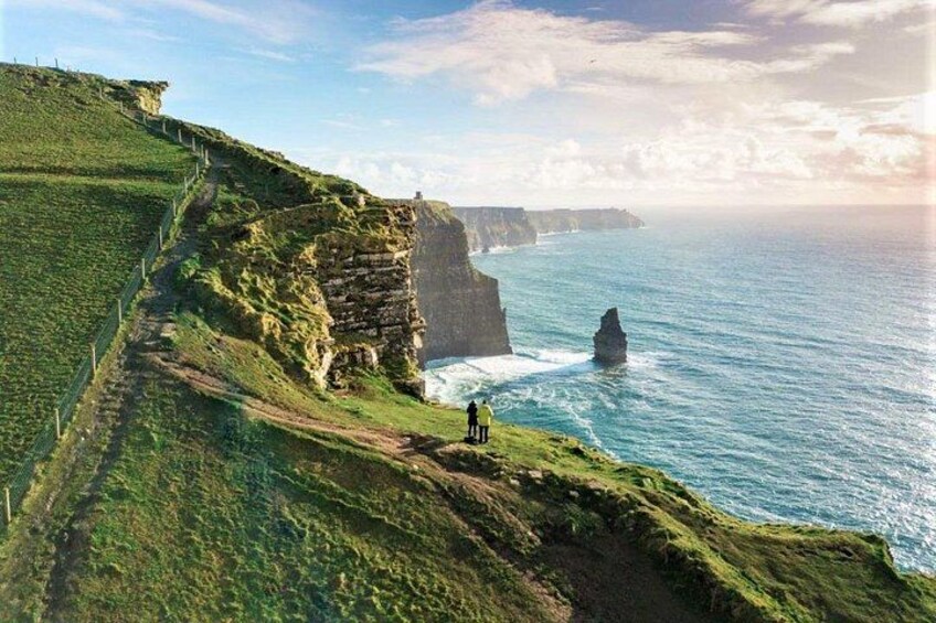 A coastal cliff with a sea view, a rocky outcrop, and a path along the cliff. 3