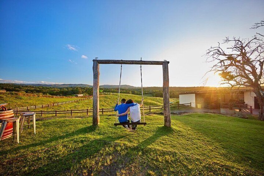 A wooden swing set in a grassy field with a clear sky. 2