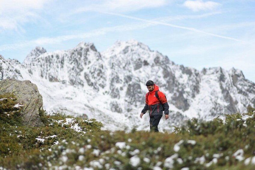 Iemand wandelt in een bergachtig gebied met besneeuwde toppen en rotsachtig terrein. 4