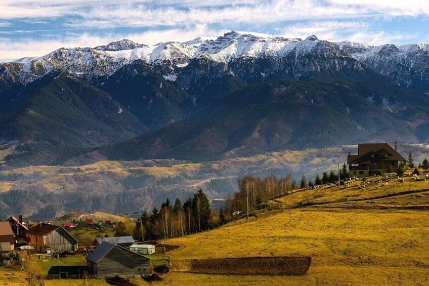 A mountainous landscape with snow-capped peaks, a small village with houses, and a clear sky. 1