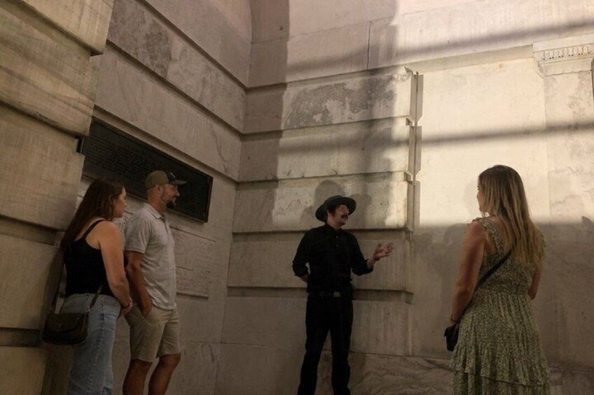 A group of people standing in a stone-walled room, one person gesturing. 2