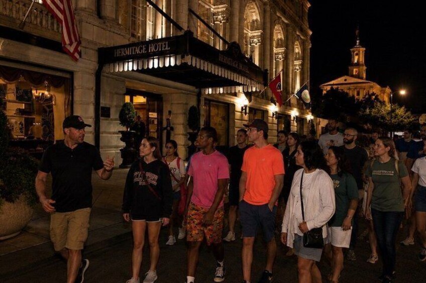 A crowd of people walking in front of a building with a sign that reads 'Hermitage Hotel.' 4