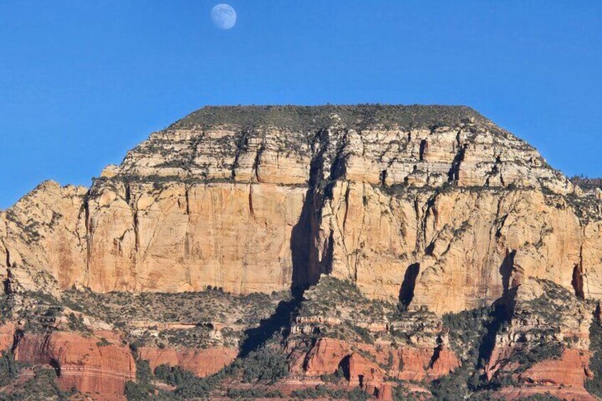 A large rock formation with a clear sky and a visible moon. 3