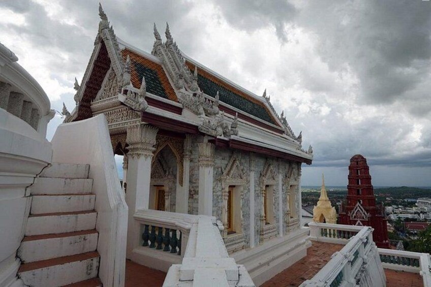 Een traditionele Thaïse tempel met uitbundige architectuur, een rode stoepa en een bewolkte lucht. 2