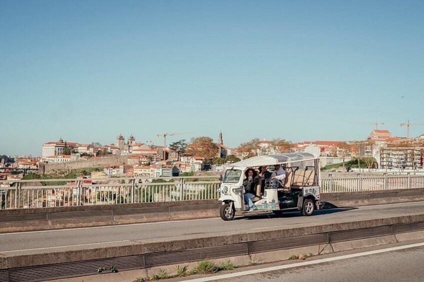 Un véhicule blanc à trois roues transportant des passagers sur un pont. 2