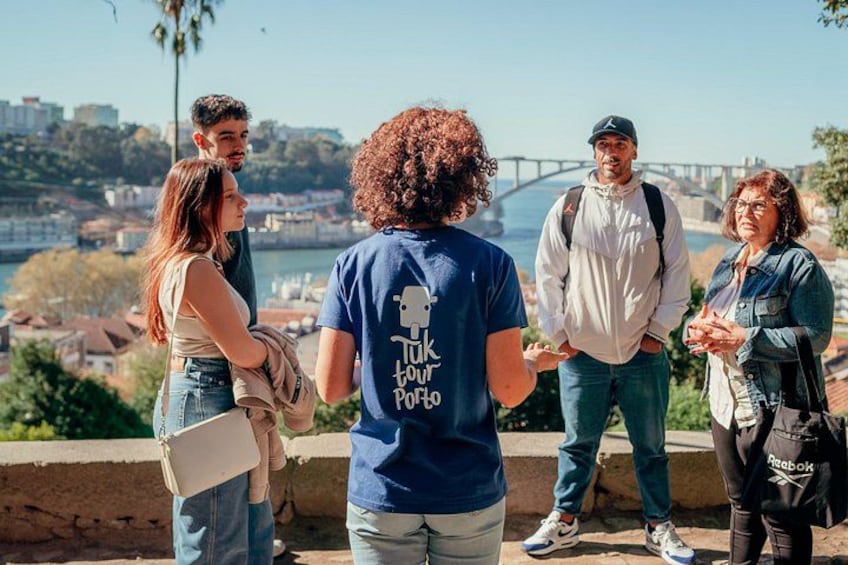 A group of people standing on a ledge overlooking a cityscape with a bridge in the background. 3