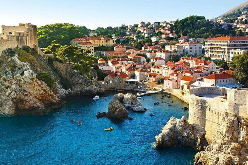 A coastal town with historic architecture, a prominent castle, and a clear blue sea. 1