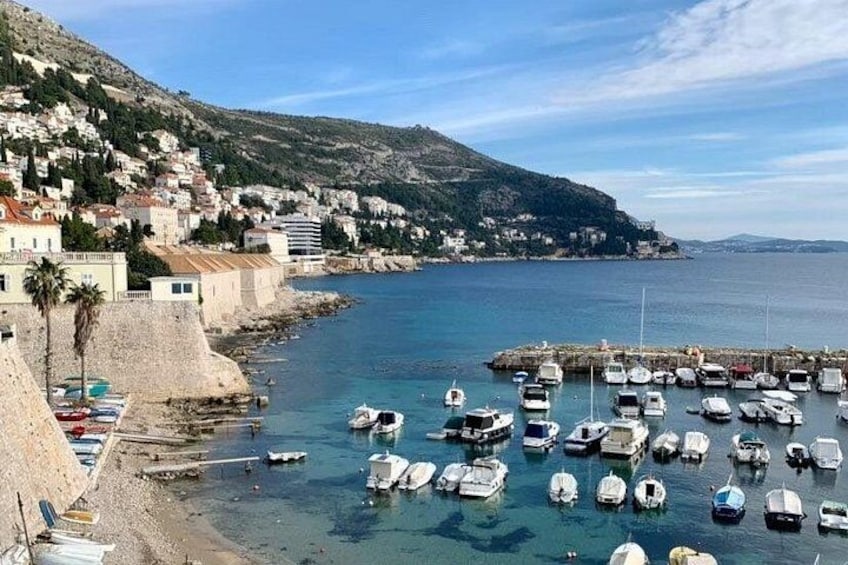 A coastal town with a marina filled with boats, a sandy beach, and residential buildings on a hillside. 4