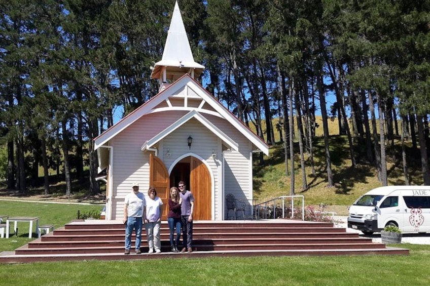 Una pequeña iglesia blanca con campanario, rodeada de árboles y césped. 3