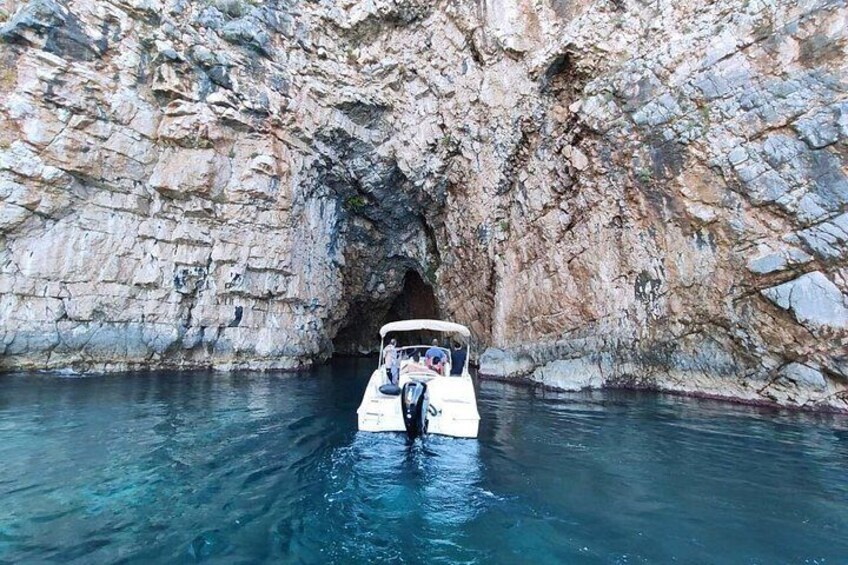 Un bote navegando por la entrada de una cueva rocosa rodeada de agua. 5