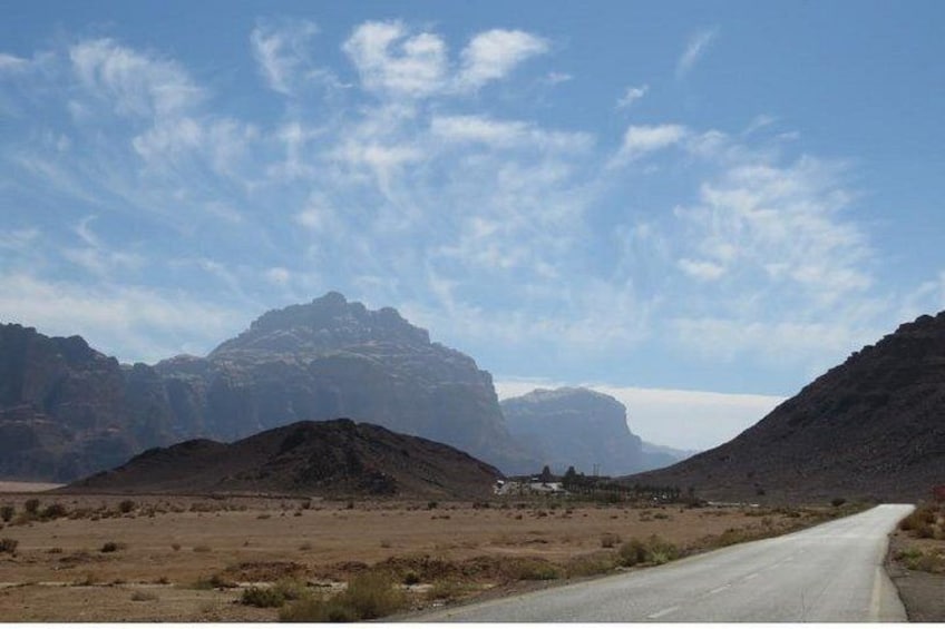 Eine Straße in einer Wüstenlandschaft, im Hintergrund Berge. 2