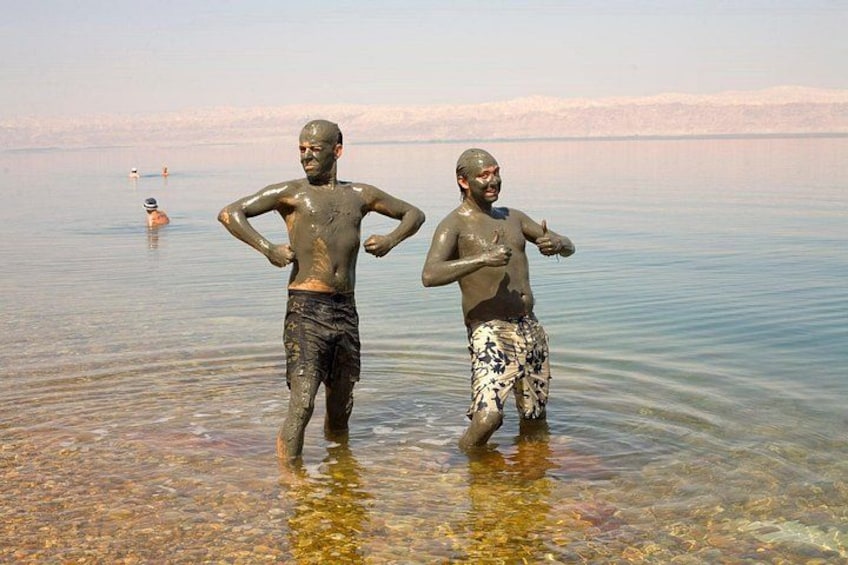 Two people standing in shallow water with a calm lake and distant mountains in the background. 2