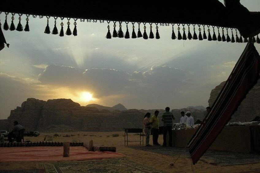 Eine Wüstenlandschaft bei Sonnenuntergang, mit Menschen und einem roten Bauwerk. 1