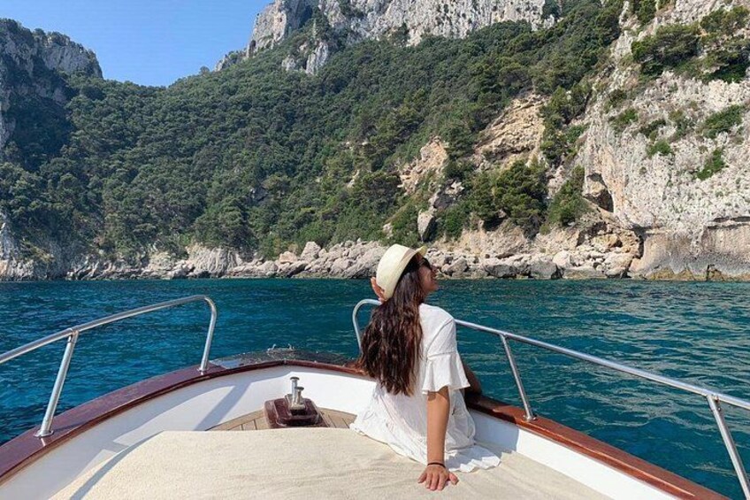 A person on a boat with a mountainous coastline in the background. 2