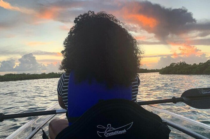 A person paddling a kayak on a body of water with a sunset in the background. 3