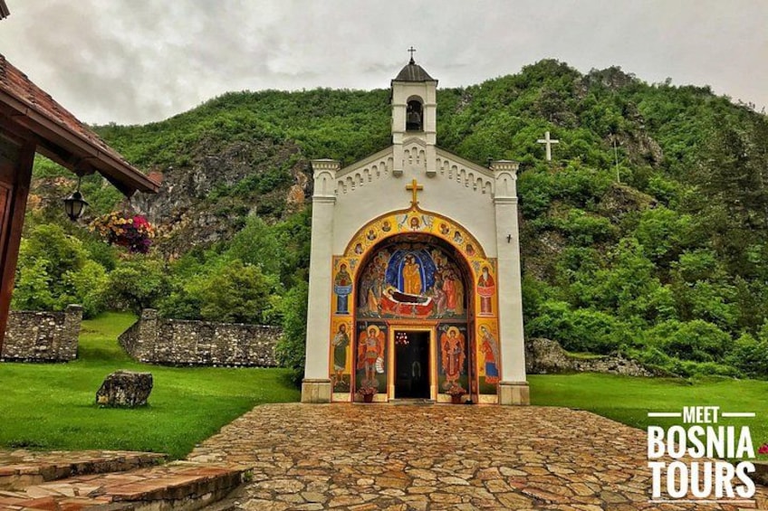 A church with a cross on top, surrounded by greenery and a stone pathway. 3