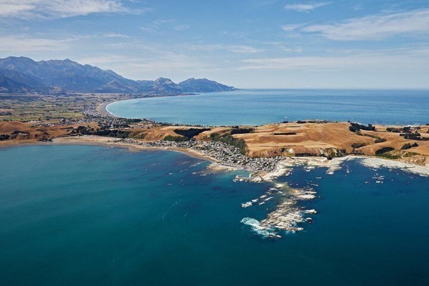 Un paysage côtier avec des montagnes en arrière-plan, une mer bleue et limpide, et une plage de sable. 3