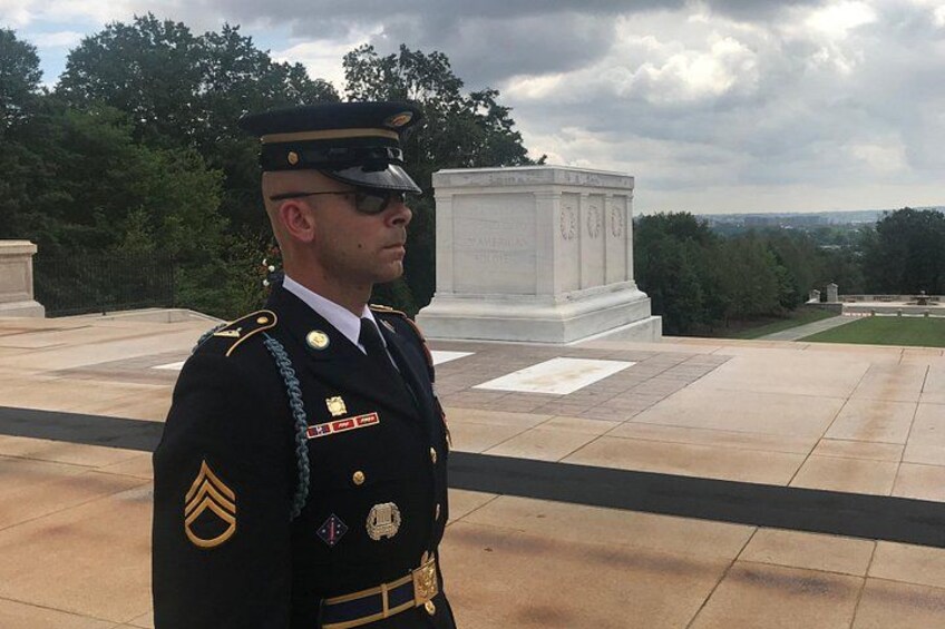 A person in a military uniform standing in front of a memorial. 2