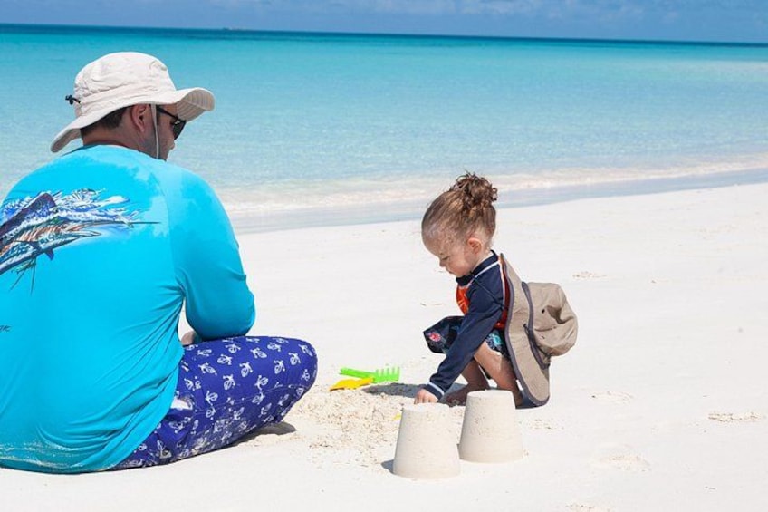 En mand og et barn leger med sand på stranden. 2
