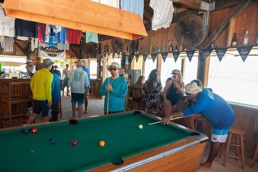 A pool table with balls, a fan, and people around. 3