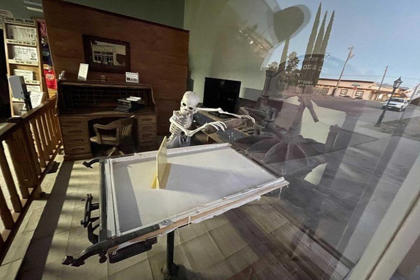 A room with a skeleton model, a desk, and a window overlooking a street. 3