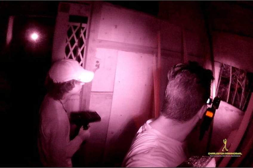 Eine Person in weißem Hemd und Mütze arbeitet an einer Holzkonstruktion, möglicherweise einer Tür oder einem Fenster, mit einem Werkzeug in der Hand. 2