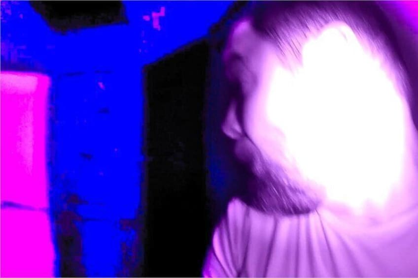 Eine Person in einem Raum mit blauen Wänden und einer rosafarbenen Lichtquelle. 3